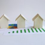 three small houses sitting on top of a piece of paper