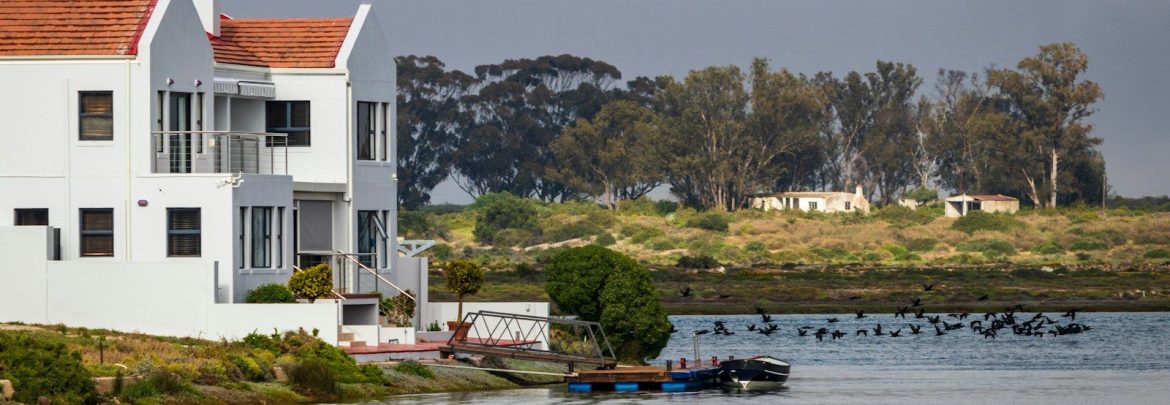 white and red concrete house beside body of water during daytime