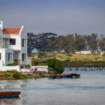 white and red concrete house beside body of water during daytime