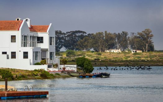 white and red concrete house beside body of water during daytime
