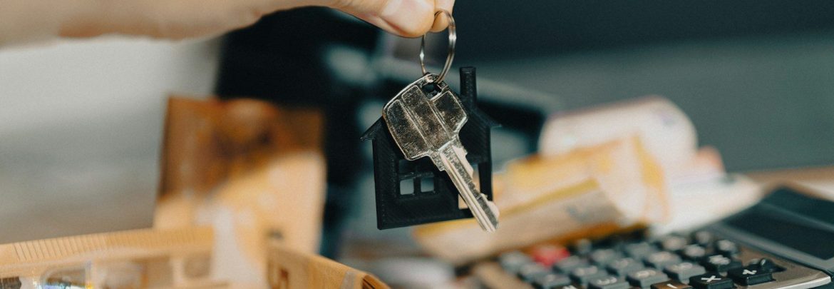 A person holding a house key in front of a calculator