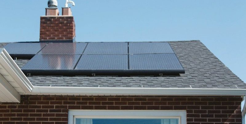 brown brick house with solar panels on roof