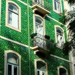 Green tiled building facade with white windows and balconies